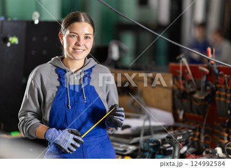 Young woman with tape measure in workshop Young woman with tape measure in workshop 124992584