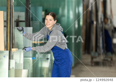 Young woman stacking glass sheets in factory Young woman stacking glass sheets in factory 124992648