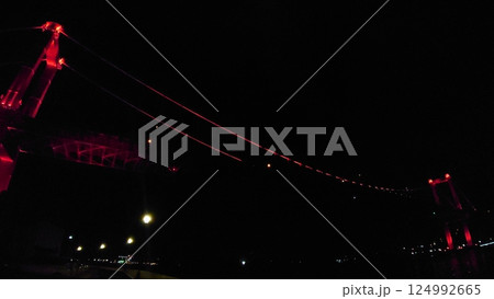 街灯が並ぶ夜道から見上げる深紅に光る橋 124992665