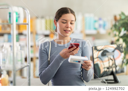 Female customer scanning QR code on box of ointment in pharmacy 124992702