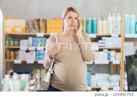 Pregnant woman having headache in drugstore Pregnant woman having headache in drugstore 124992703