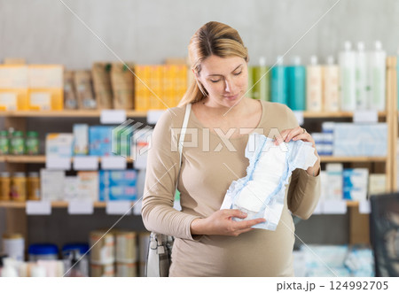 Pregnant woman in drugstore chooses diapers for newborn Pregnant woman in drugstore chooses diapers for newborn 124992705