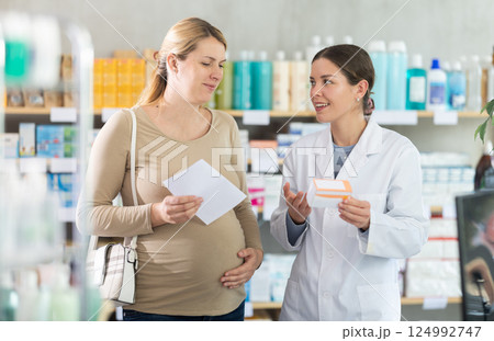 Drug store staff offer supplements to pregnant woman customer 124992747