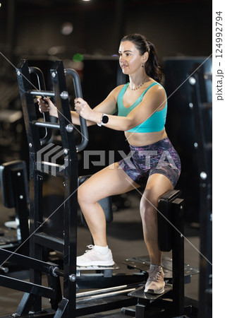 Woman uses leg abduction machine to strengthen muscles Woman uses leg abduction machine to strengthen muscles 124992794