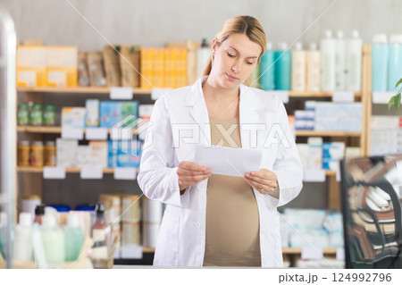 Pregnant woman pharmacist checking prescription on computer 124992796
