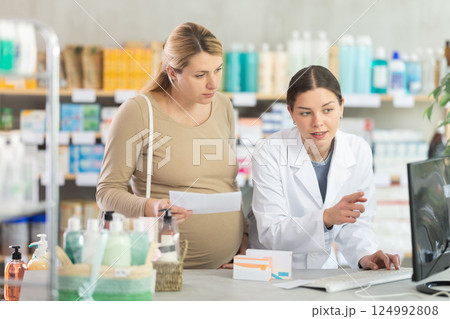 Pharmacist verifying prescribed medication for pregnant woman Pharmacist verifying prescribed medication for pregnant woman 124992808