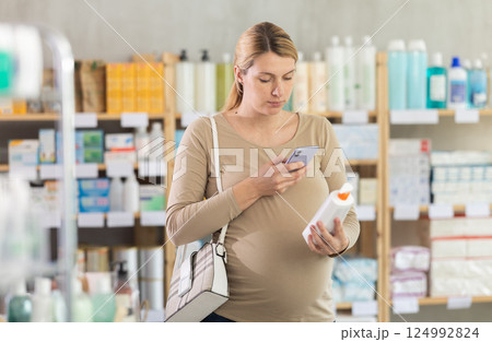 Pregnant woman scanning qr code of cream 124992824