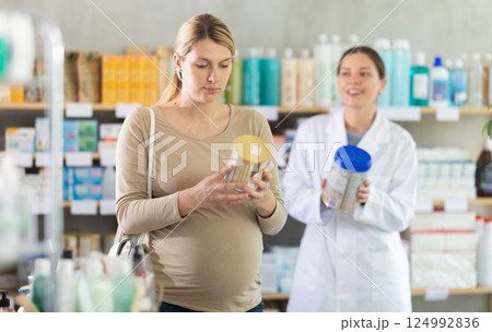 Pregnant woman choosing baby formula with help of pharmacist Pregnant woman choosing baby formula with help of pharmacist 124992836