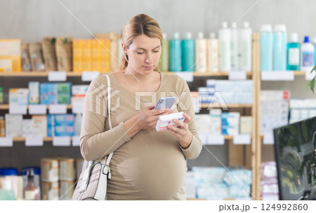 Pregnant woman scanning qr code of pills Pregnant woman scanning qr code of pills 124992860