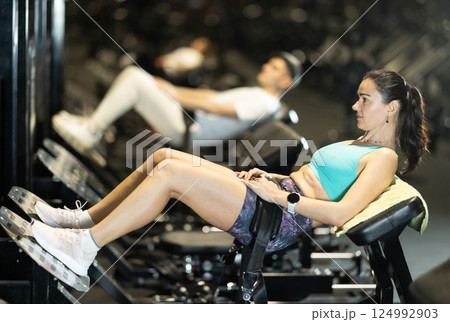 Woman performing hip thrusts on glute bridge machine at gym 124992903