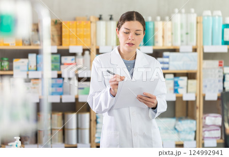 Female pharmacist writing down inventory results at pharmacy 124992941
