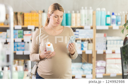 Pregnant woman chooses diaper rash cream in pharmacy 124992986