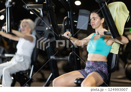 Woman using chest press machine during workout at gym 124993007