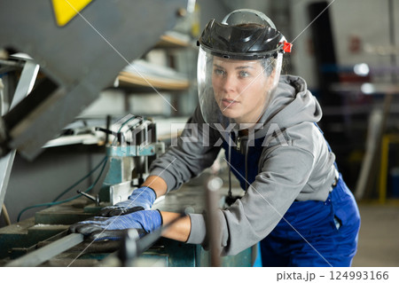 Young woman puts steel part on machine 124993166