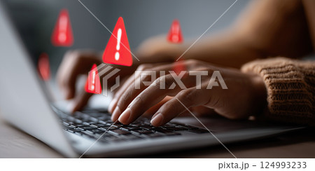 person typing laptop with red warning signs floating above, symbolizing online security risks 124993233