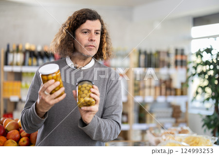 customer in a store chooses olives customer in a store chooses olives 124993253