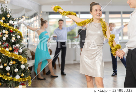 Teen boy and girl dancing waltz in couple during lesson at studio in New Year atmosphere Teen boy and girl dancing waltz in couple during lesson at studio in New Year atmosphere 124993332