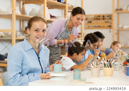Teenage girl painting handmade ceramic cup with brush Teenage girl painting handmade ceramic cup with brush 124993419