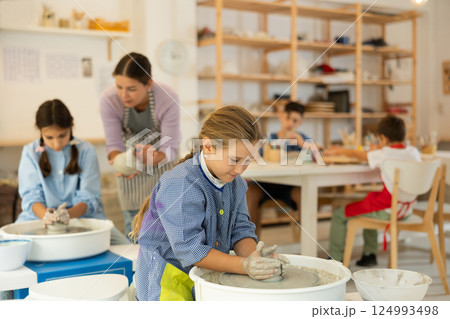 Girl working at a potter's wheel with clay 124993498