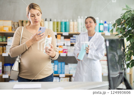 Pregnant woman buyer scans shampoo qr code with woman pharmacist 124993606
