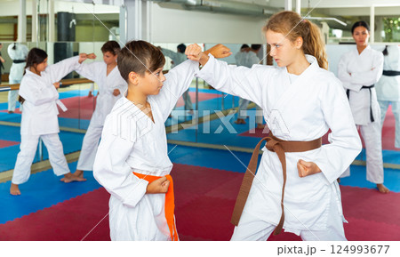 Boys and girls exercising karate moves on group training Boys and girls exercising karate moves on group training 124993677