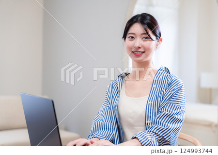自宅で笑顔でリモート会議に参加する若い女性 自宅で笑顔でリモート会議に参加する若い女性 124993744
