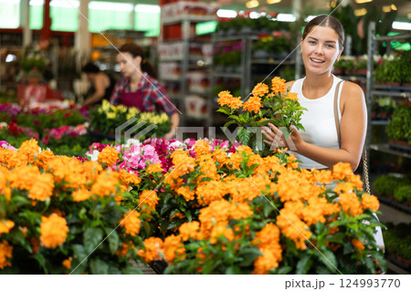 Young woman choosing crossandra in pot 124993770