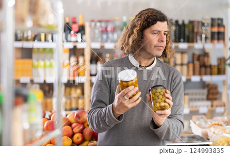 Adult man choosing olives in grocery store Adult man choosing olives in grocery store 124993835