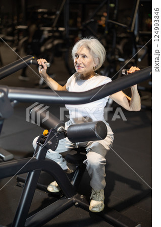 Elderly woman working out on lat pulldown machine in gym Elderly woman working out on lat pulldown machine in gym 124993846