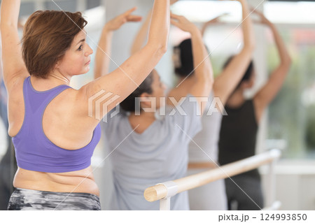 Group of women stand in fifth position at barre 124993850