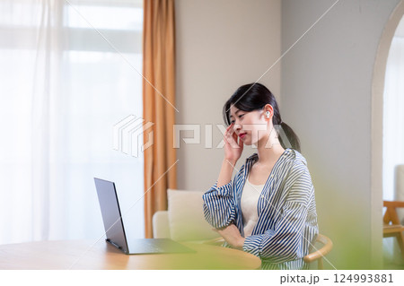 在宅勤務をしながら頭を抱える若い女性 在宅勤務をしながら頭を抱える若い女性 124993881