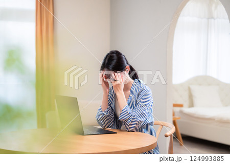 在宅勤務をしながら頭を抱える若い女性 在宅勤務をしながら頭を抱える若い女性 124993885