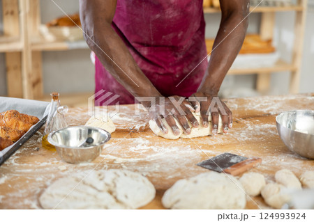 Hands of African baker kneading dough on floury table 124993924