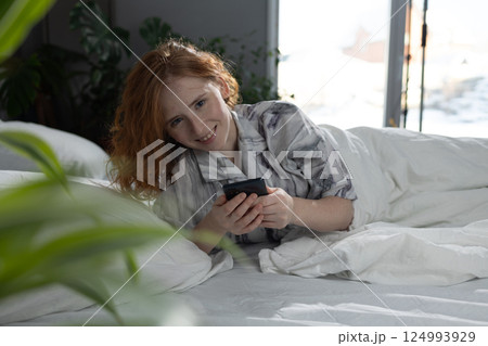 Experience a Cozy Morning while using a Smartphone comfortably in Bed, enjoying life 124993929