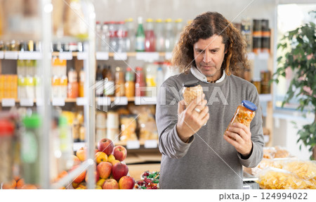 Male shopper choosing canned beans and lentils in supermarket Male shopper choosing canned beans and lentils in supermarket 124994022