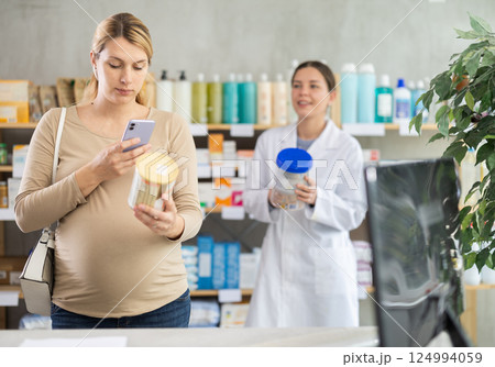 Pregnant woman buyer scans baby formula qr code with woman pharmacist Pregnant woman buyer scans baby formula qr code with woman pharmacist 124994059