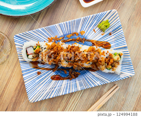 Delicious sushi in Japanese restaurant. Plate of Karikari roll with crab, avocado, cucumber, onion and served with soy sauce 124994188