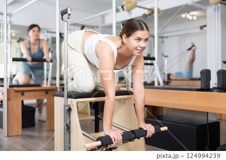 Young girl practicing pilates stretching exercises on combo chair 124994239