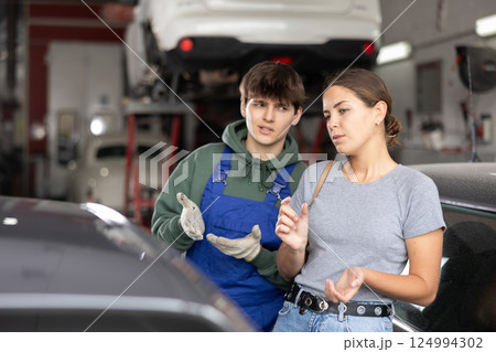 Guy car repair shop worker consulting woman client Guy car repair shop worker consulting woman client 124994302