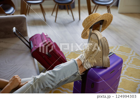 Cropped shot of female traveler legs in boots on luggage suitcase Cropped shot of female traveler legs in boots on luggage suitcase 124994303