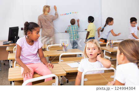 Girl and boy are sitting at the desk and talking about life in classroom Girl and boy are sitting at the desk and talking about life in classroom 124994304