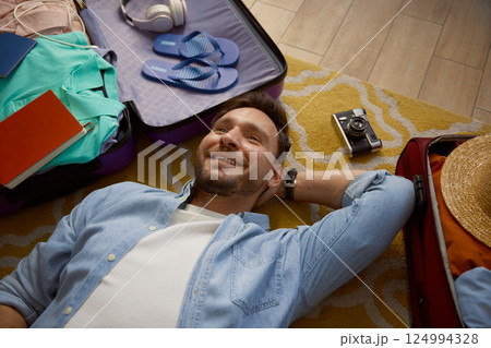 Young man lying on floor dreaming about future vacation trip Young man lying on floor dreaming about future vacation trip 124994328