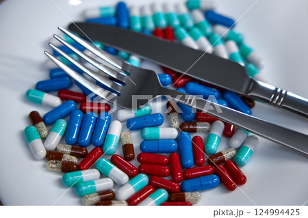 Healthcare supplement and medical pills on plate with knife and fork Healthcare supplement and medical pills on plate with knife and fork 124994425