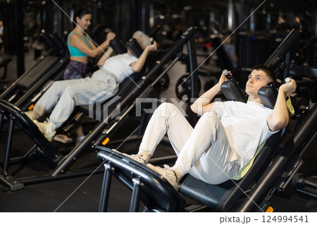 Guy using hack squat machine in modern gym Guy using hack squat machine in modern gym 124994541