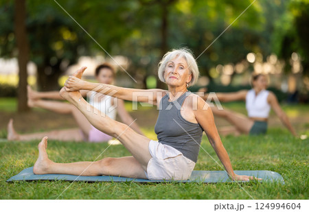 Elderly woman participating in outdoor yoga session in summer park 124994604
