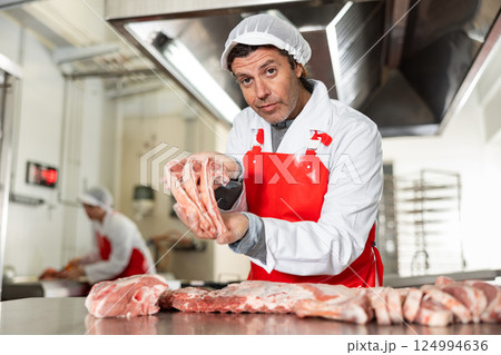 Male meat seller demonstrating raw pork ribs 124994636