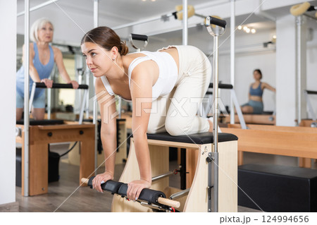 Young girl doing exercises on wunda chair in pilates studio Young girl doing exercises on wunda chair in pilates studio 124994656