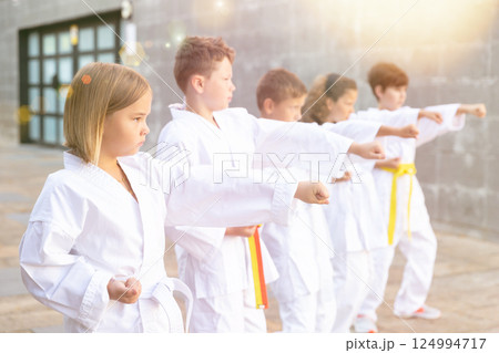 Group of schoolchildren practicing karate at schoolyard 124994717