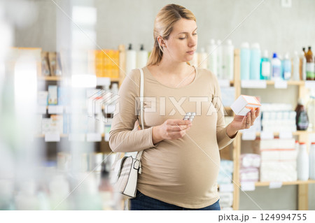 Pregnant woman chooses pills at pharmacy Pregnant woman chooses pills at pharmacy 124994755