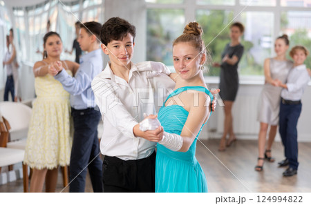Positive teen boy and girl are dancing classic version of waltz in couple during lesson at studio 124994822
